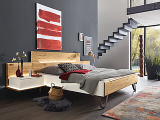 Schlafzimmer Jovanna: Liegenbett mit Holzkopfteil in Absetzung, ca. 180 x 200 cm, Ansatzpaneel inkl. Ablageboden in Absetzung, ca. B 65, H 55, T 55 cm, Aufsatzkonsole für Ansatzpaneel, ca. 59, H 22, T 45 cmLack weiß/Absetzung Wildeiche massiv