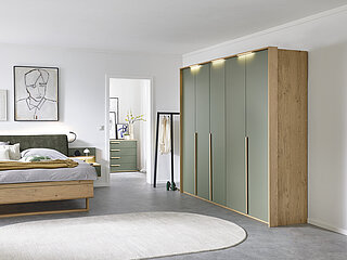 Vorschlag 701, Balkeneiche furniert, Absetzung Lack Jungle Green, bestehend aus Drehtürenschrank 6-türig, 3 Griffstangen in Eiche massiv, ca. B 299, H 229, T 60 cm, Doppelbett in Luxushöhe, ca. B 189, H 105, T 222 cm, Liegefläche ca. 180 x 200 cm, BSH 48,6 cm, Polsterkopfteil "Luna" in Stoff Maranta Jungle Green, 100 % Polyester, Fußteil mit Lisene, unten abgerundet und Kufe in Eiche, 2 Hängekonsolen mit je 1 Schubkasten, jeweils ca. B 60, H 23, T 46 cm. Zubehör: Passepartout ohne Beleuchtung (903004); 3er-Set LED-Stabbeleuchtung (90353); Paneelaufsatz links und rechts mit Holzboden (20216, 20226); indirekte LED-Holzbodenbeleuchtung (80027); 2er-Set LED-Flex-Leuchte Anthrazit, USB-Anschluss (80033).