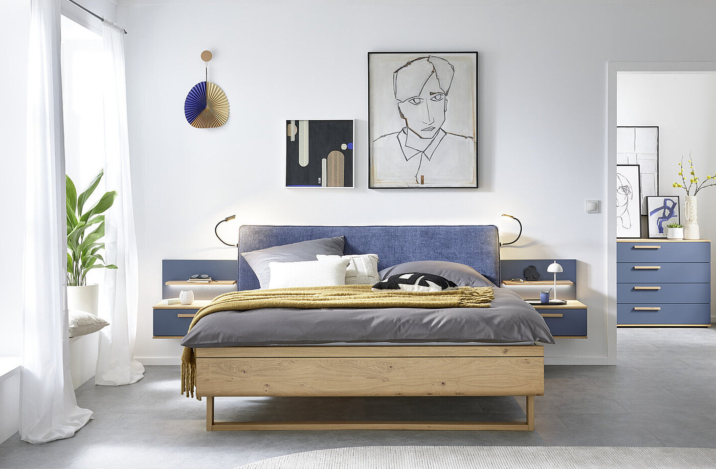 MR11523_B_Malin - 15.jpg in Balkeneiche furniert, Absetzung Lack Lagunenblau, Doppelbett in Luxushöhe, ca. B 189, H 105, T 222 cm, Liegefläche ca. 180 x 200 cm, BSH 48,6 cm, Polsterkopfteil "Luna" in Stoff Maranta Lagunenblau, 100 % Polyester, Fußteil mit Lisene, unten abgerundet und Kufe in Eiche, 2 Hängekonsolen mit je 1 Schubkasten, jeweils ca. B 60, H 23, T 46 cm. Zubehör: Paneelaufsatz links und rechts mit Holzboden (20216, 20226); indirekte LED-Holzbodenbeleuchtung (80027); 2er-Set LED-Flex-Leuchte Anthrazit, USB-Anschluss (80033).