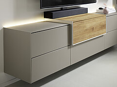 Sideboard Vorschlag 821-16-75-80-3L-1, Mattglas fango (PG 5) / Eiche massiv, gebürstet, ca. B 262, H 53, T 42 cm. Zubehör: Hängebeschlag (1), 3 x Klappe mit Push-to-open (PUSH), 3 x Schubkasten mit Push-to-open (PUSH), LED-Band für Oberboden (645), LED-Band für Oberboden (656), Soundbarhaube schwarz (680-00-00-3-0-00-0), TV-Halterung schwenkbar (685), Trafo und Fernbedienung (640)