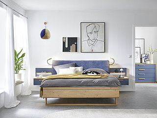 in Balkeneiche furniert, Absetzung Lack Lagune Blau, Doppelbett in Luxushöhe, ca. B 189, H 105, T 222 cm, Liegefläche ca. 180 x 200 cm, BSH 48,6 cm, Polsterkopfteil "Luna" in Stoff Maranta Lagune blau, 100 % Polyester, Fußteil mit Lisene, unten abgerundet und Kufe in Eiche, 2 Hängekonsolen mit je 1 Schubkasten, jeweils ca. B 60, H 23, T 46 cm. Zubehör: Paneelaufsatz links und rechts mit Holzboden (20216, 20226); indirekte LED-Holzbodenbeleuchtung (80027); 2er-Set LED-Flex-Leuchte Anthrazit, USB-Anschluss (80033).